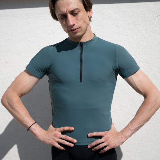 Denys Cherevychko wearing a teal athletic shirt with a zipper against a white background