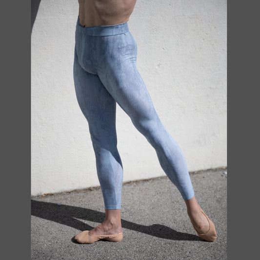 Denys Cherevychko wearing light blue leggings against a white wall.