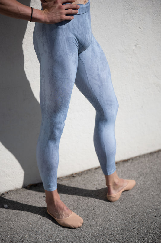 Denys Cherevychko wearing light blue leggings against a white wall.