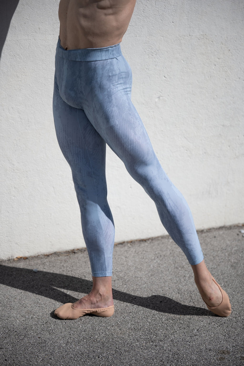 Denys Cherevychko wearing light blue leggings against a white wall.