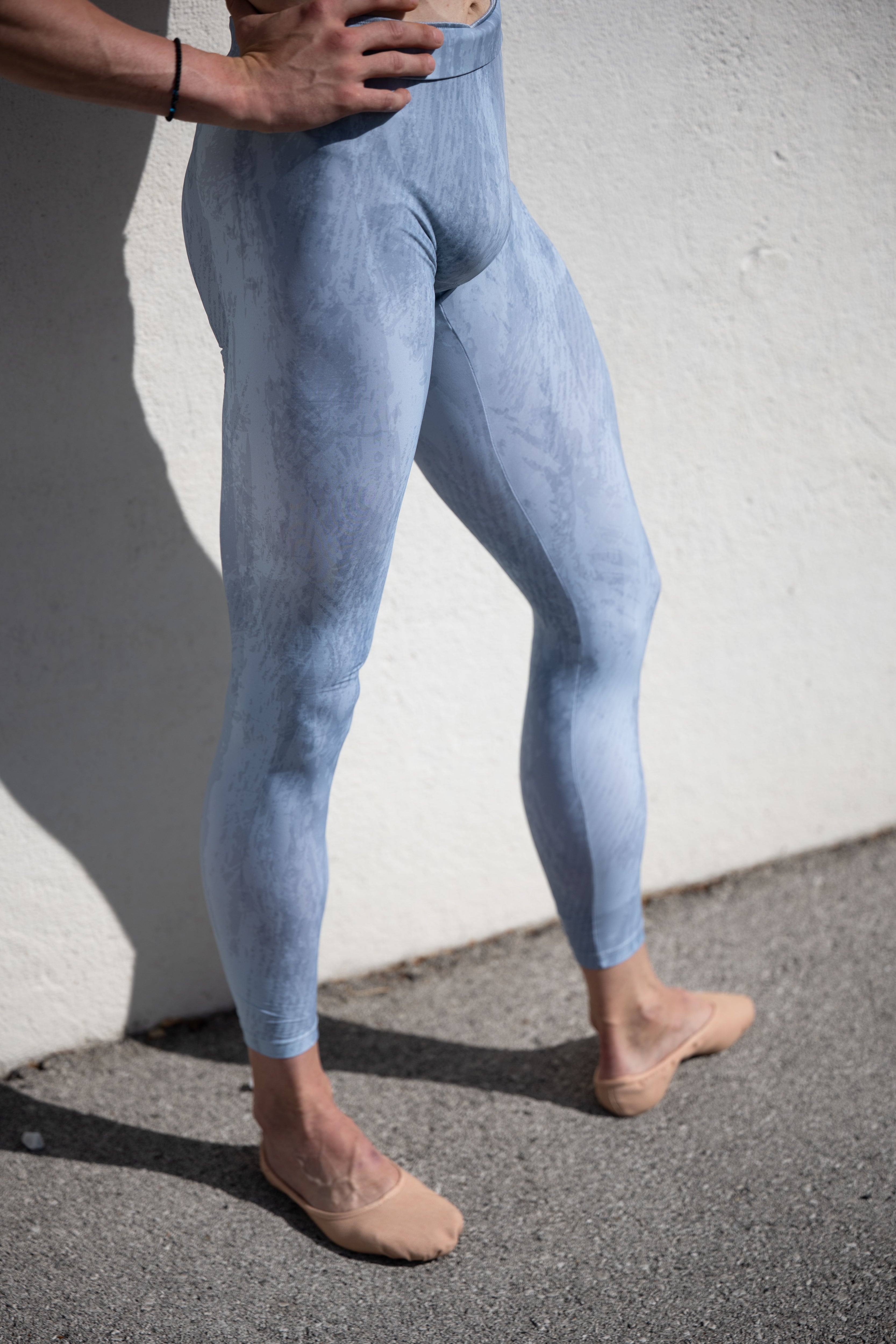 Denys Cherevychko wearing light blue leggings against a white wall.