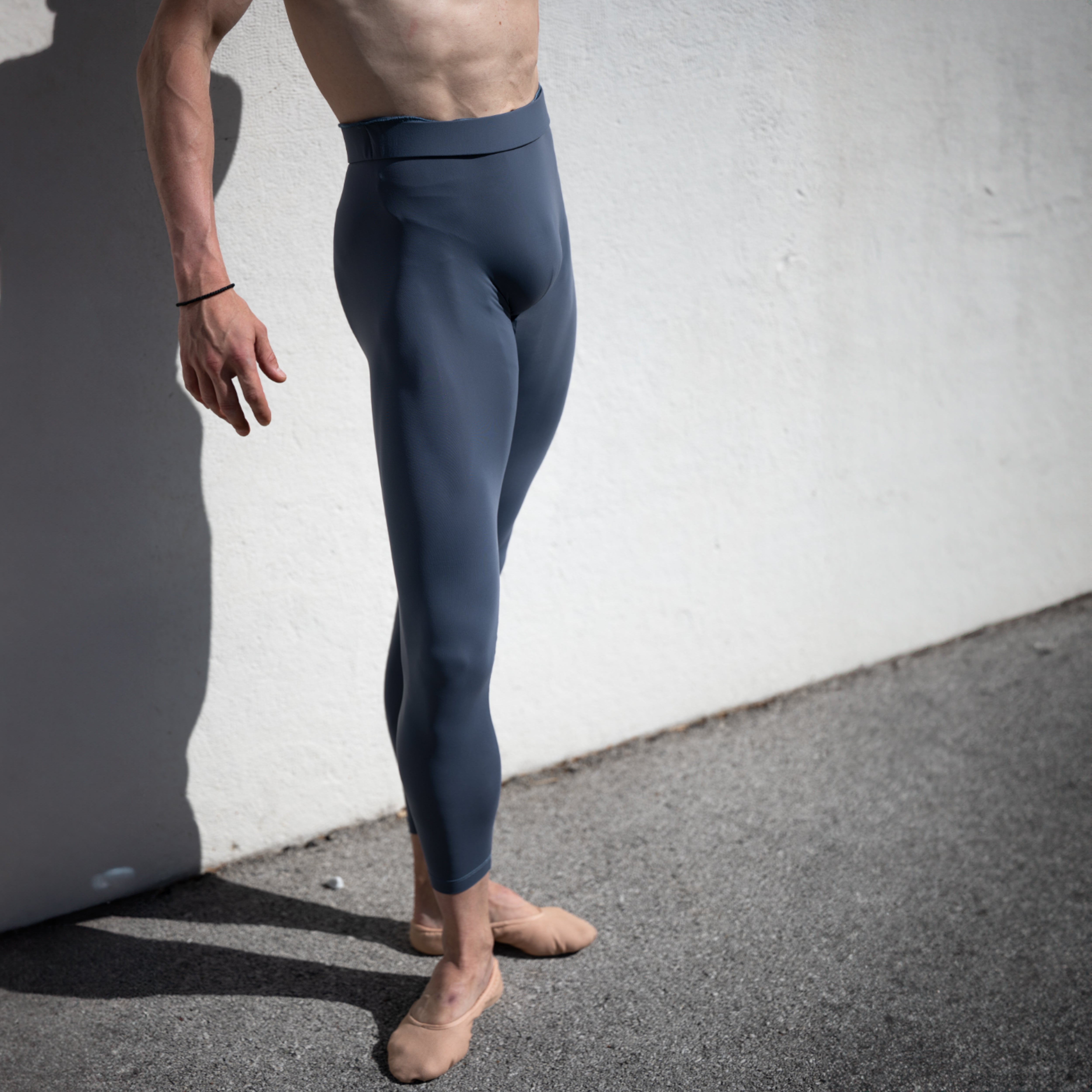 Denys Cherevychko wearing grey leggings against a white wall.