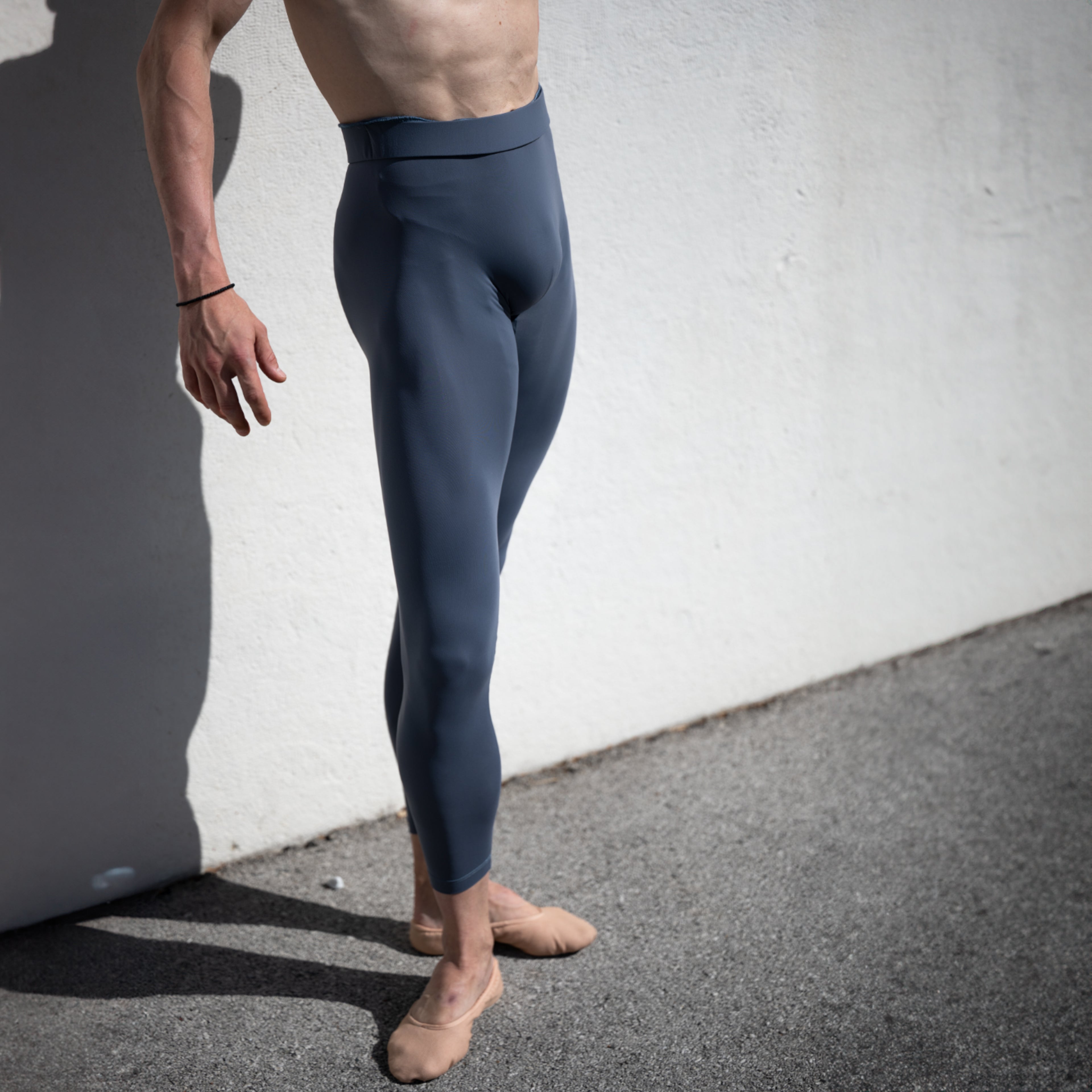 Denys Cherevychko wearing grey leggings against a white wall.
